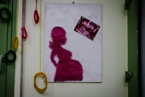 Creative wall art featuring a string silhouette of a pregnant woman with a pregnancy scan photo.